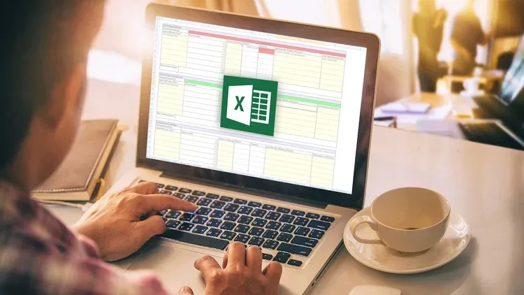 Người đàn ông sử dụng phần mềm Excel trên máy tính xách tay cùng với tách cà phê trên bàn tại trung tâm đào tạo tin học và tiếng Anh Edusa.