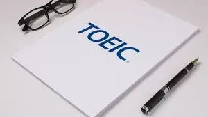 Bài thi TOEIC trên bàn với một cặp kính và bút bi