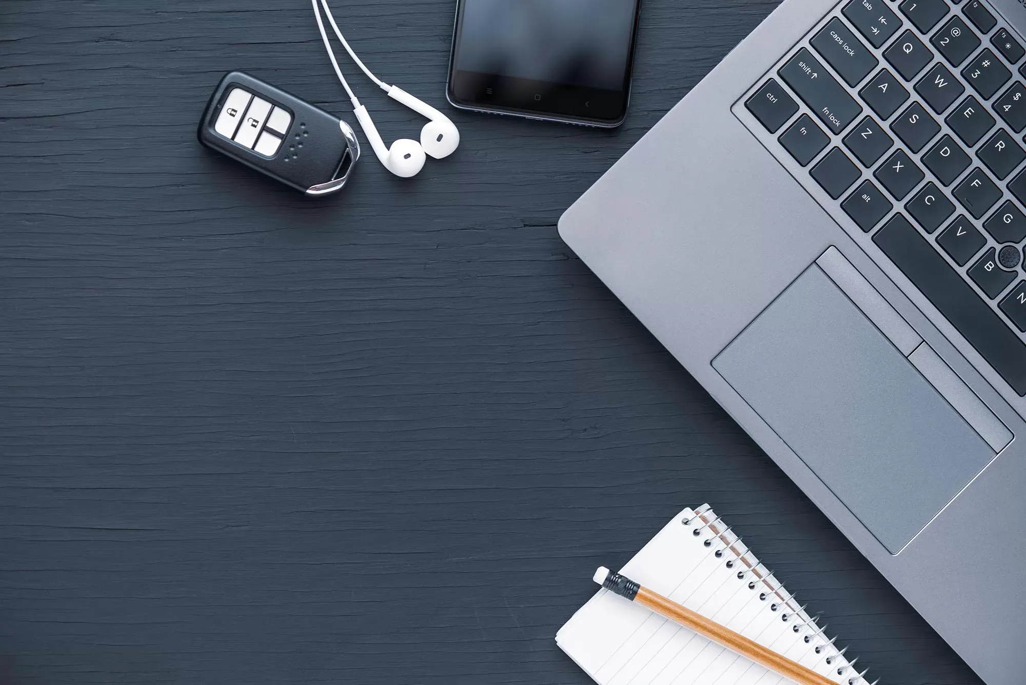 Bàn làm việc với laptop, điện thoại, sổ tay và chìa khóa ô tô